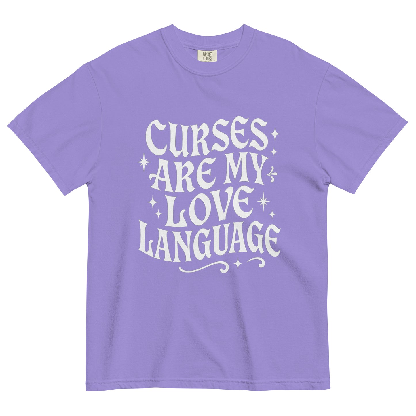 Purple t-shirt laid flat showing white gothic text reading ‘Curses Are My Love Language,’ with tiny star illustrations around the phrase.