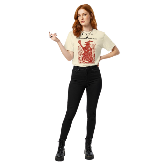 Woman wearing ivory “I don’t need snow man” T-shirt with red witch design, styled casually with black jeans.