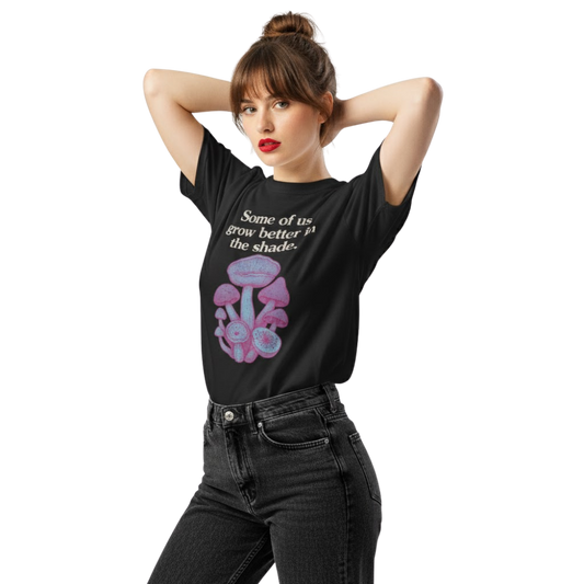 Model wearing black “Some of us grow better in the shade” t-shirt featuring mushroom artwork and moody minimalist text, styled with black jeans for an alt look.