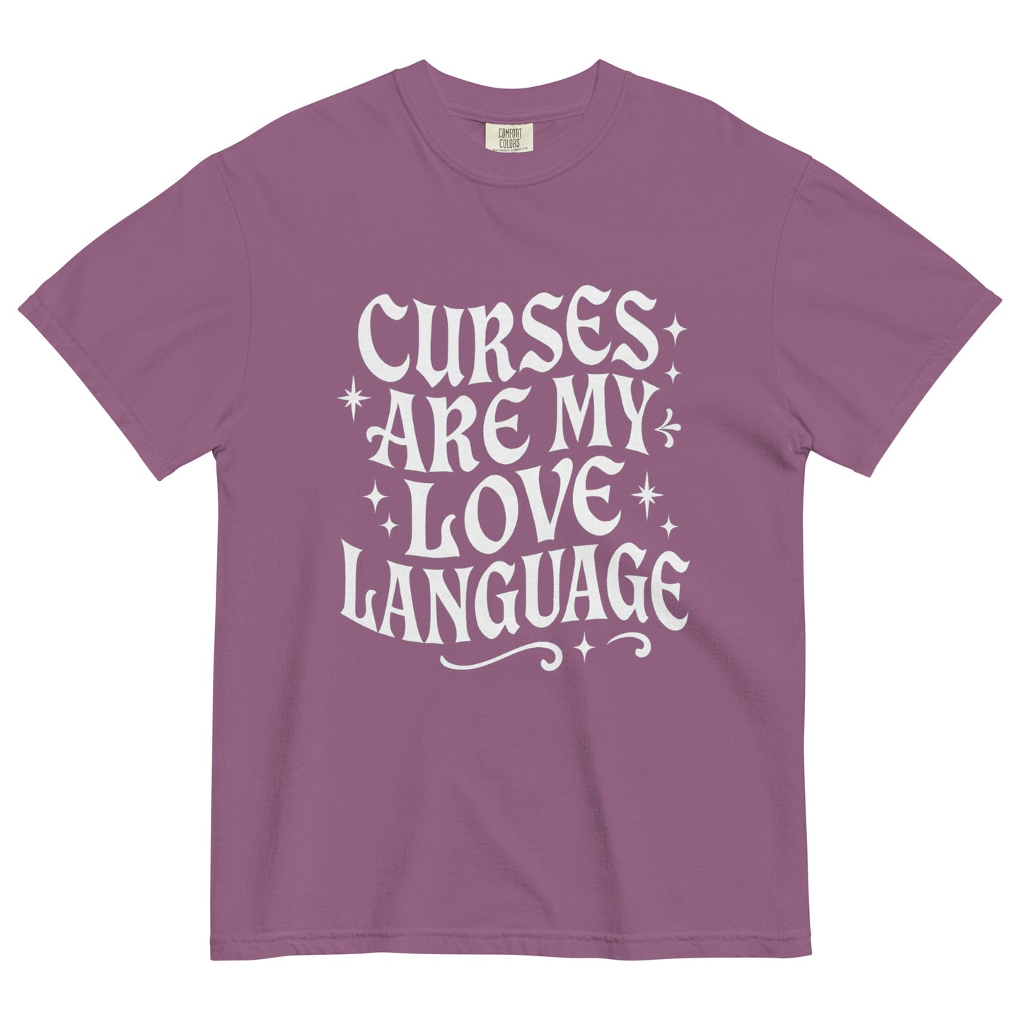 Plum purple t-shirt laid flat with white gothic lettering that says ‘Curses Are My Love Language,’ accented by small stars.