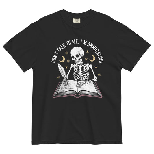 Skeleton writing in a book under moon and stars with quote ‘Don’t talk to me, I’m annotating’ on a black t-shirt.