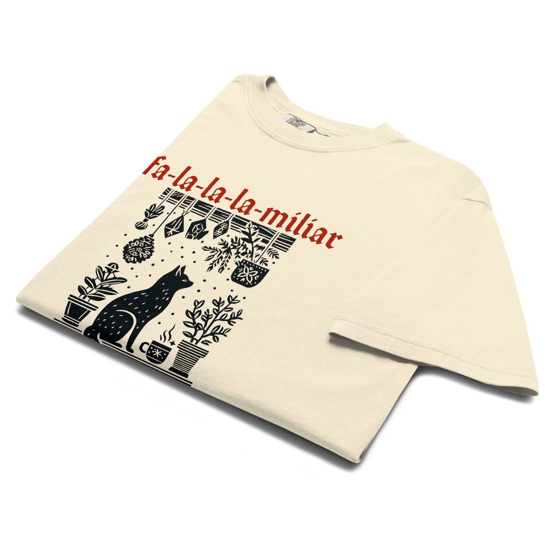 Folded Fa-La-La-La-Miliar Familiar Cat Holiday Tee highlighting the witchy cat and hanging herb design with festive red type.