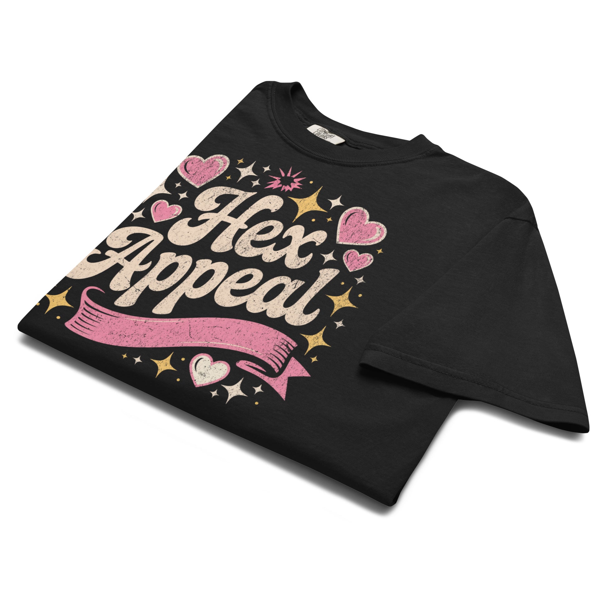 Folded black “Hex Appeal” t-shirt flat lay with glittery pink lettering and heart details, perfect for witchy fashion lovers with a sense of humor.