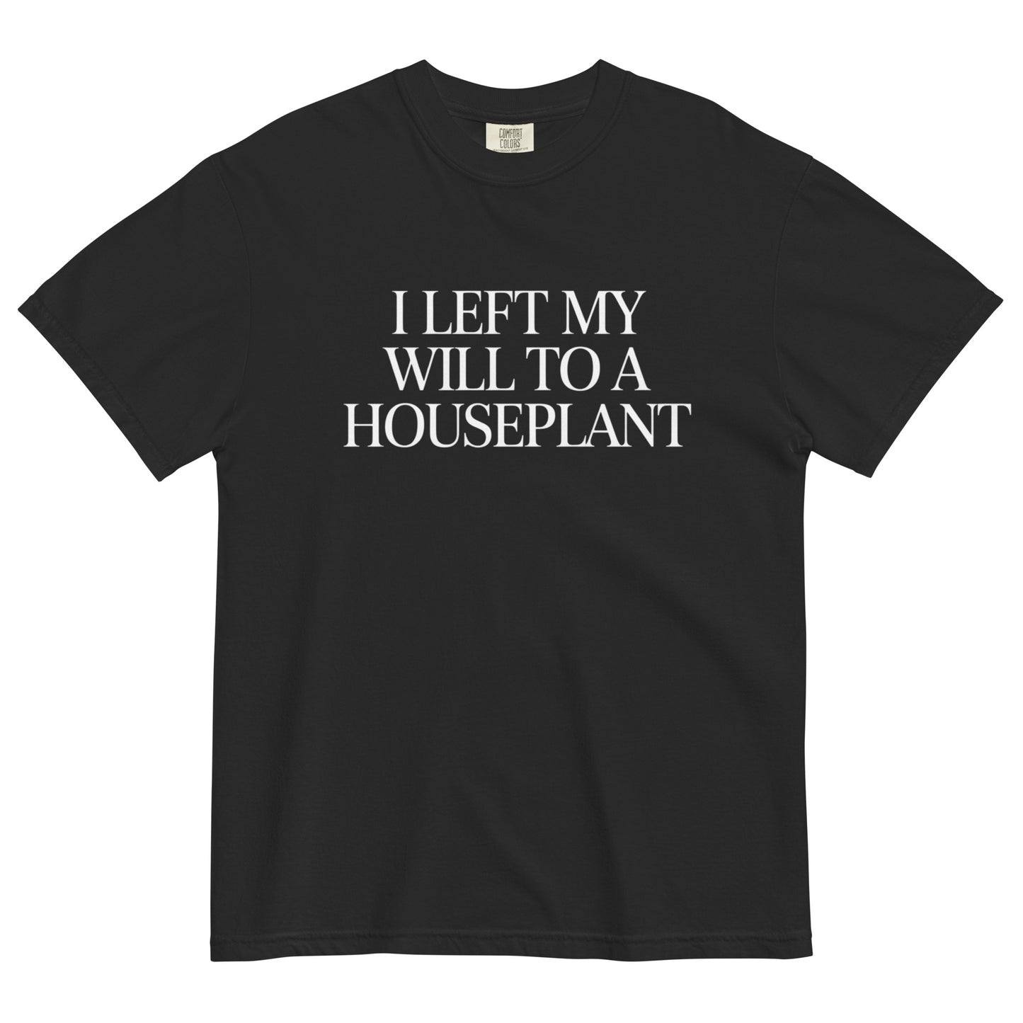 Black t-shirt lay flat featuring white serif text reading “I Left My Will to a Houseplant,” a darkly funny minimalist tee for plant lovers with a morbid sense of humor.