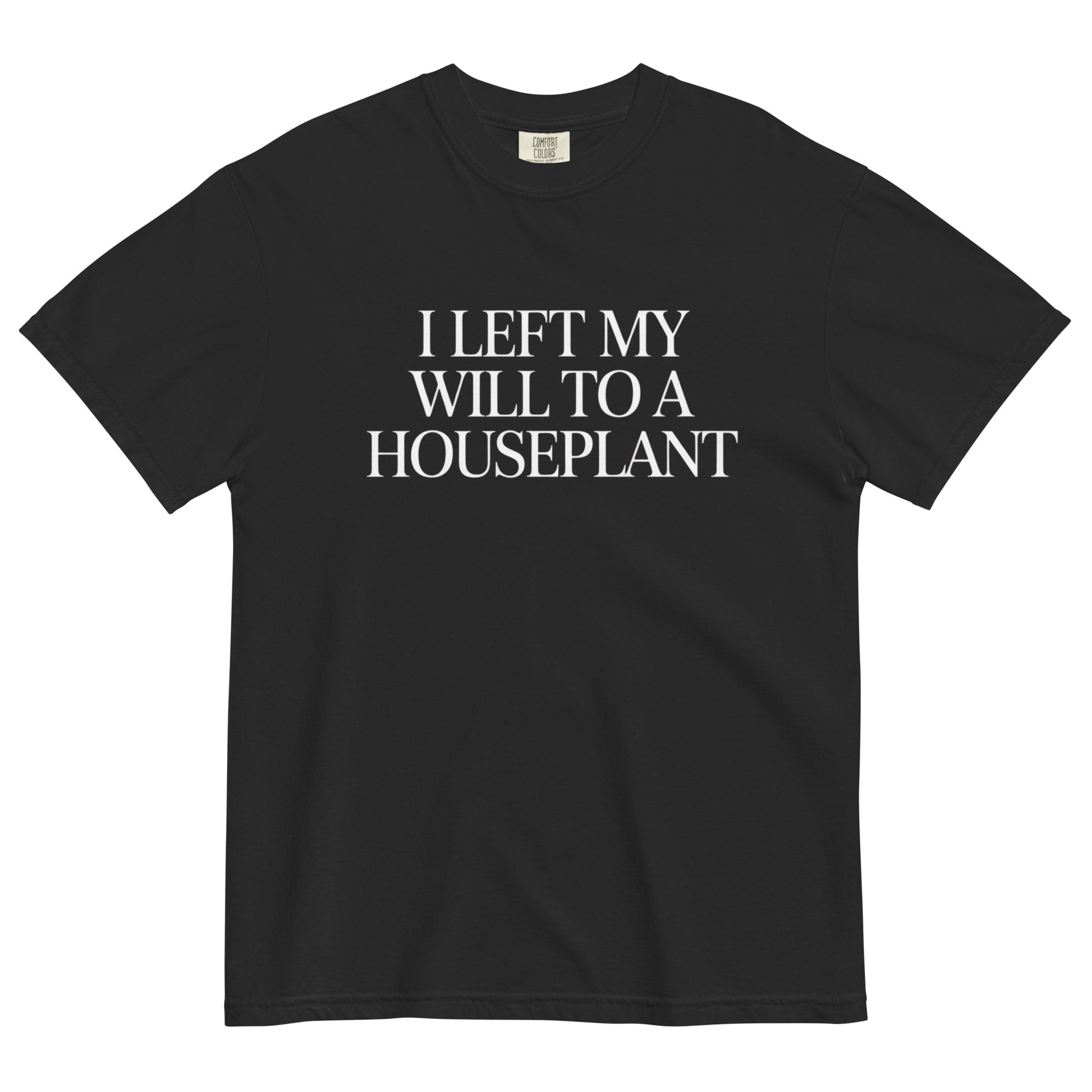 Black t-shirt lay flat featuring white serif text reading “I Left My Will to a Houseplant,” a darkly funny minimalist tee for plant lovers with a morbid sense of humor.