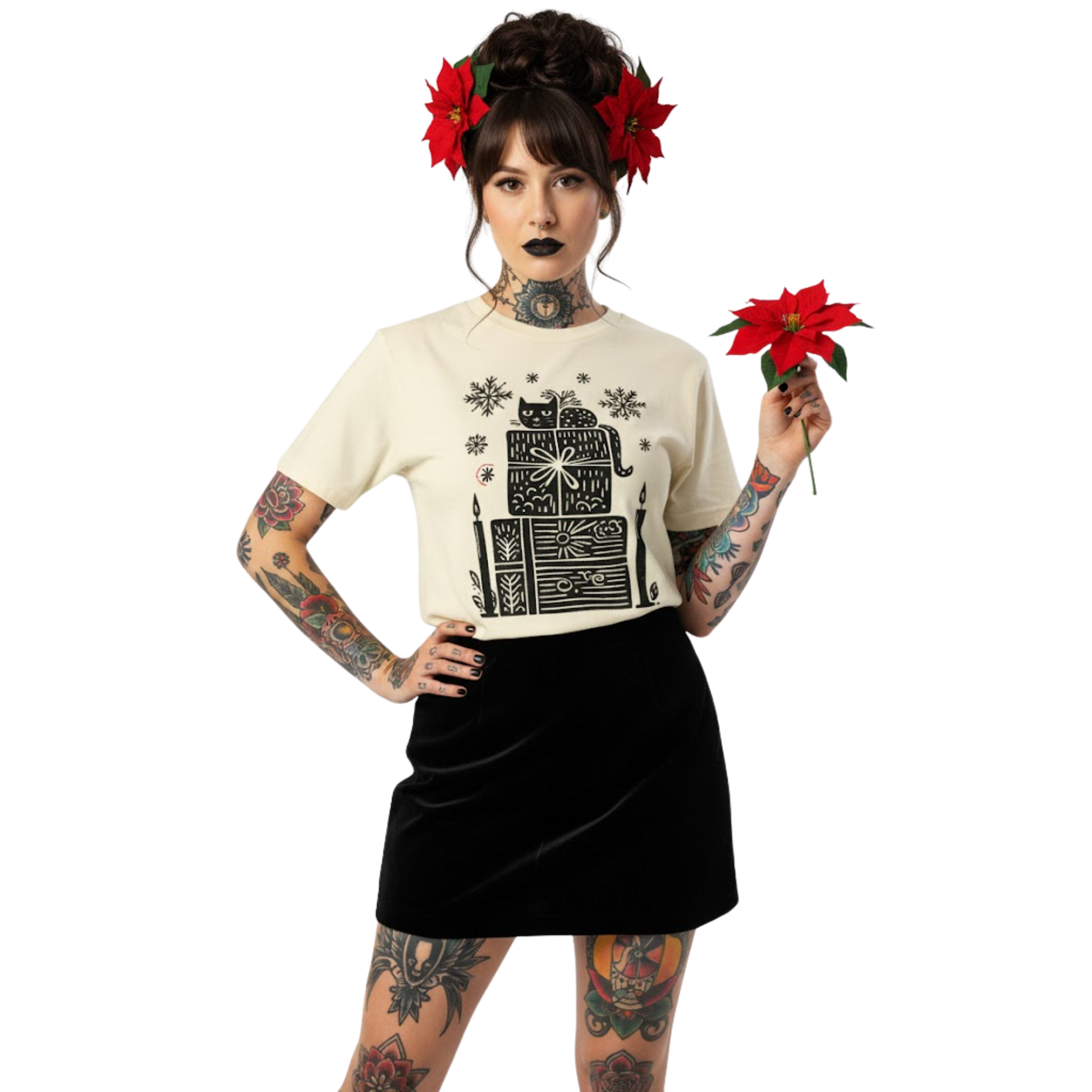 Woman wearing ivory witchy holiday T-shirt featuring candle and gift stack design, styled with black skirt and poinsettia bouquet.