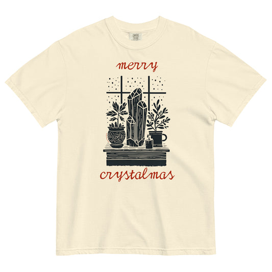 Ivory Comfort Colors T-shirt with “Merry Crystalmas” design featuring crystals, candles, and plants, shown lay flat on white background.
