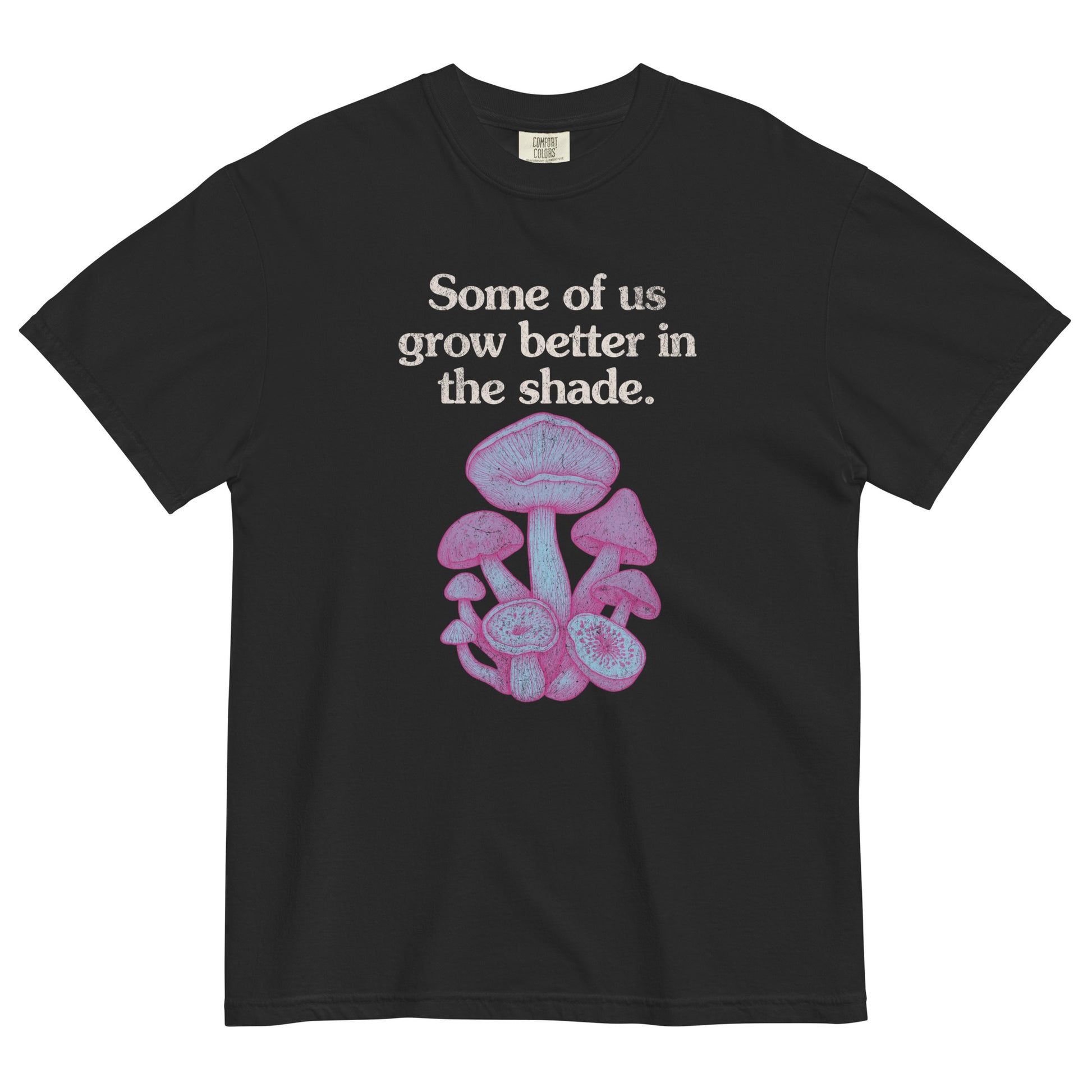 Black t-shirt lay flat with text reading “Some of us grow better in the shade” above a cluster of pink and purple mushrooms, a dreamy gothic botanical tee.