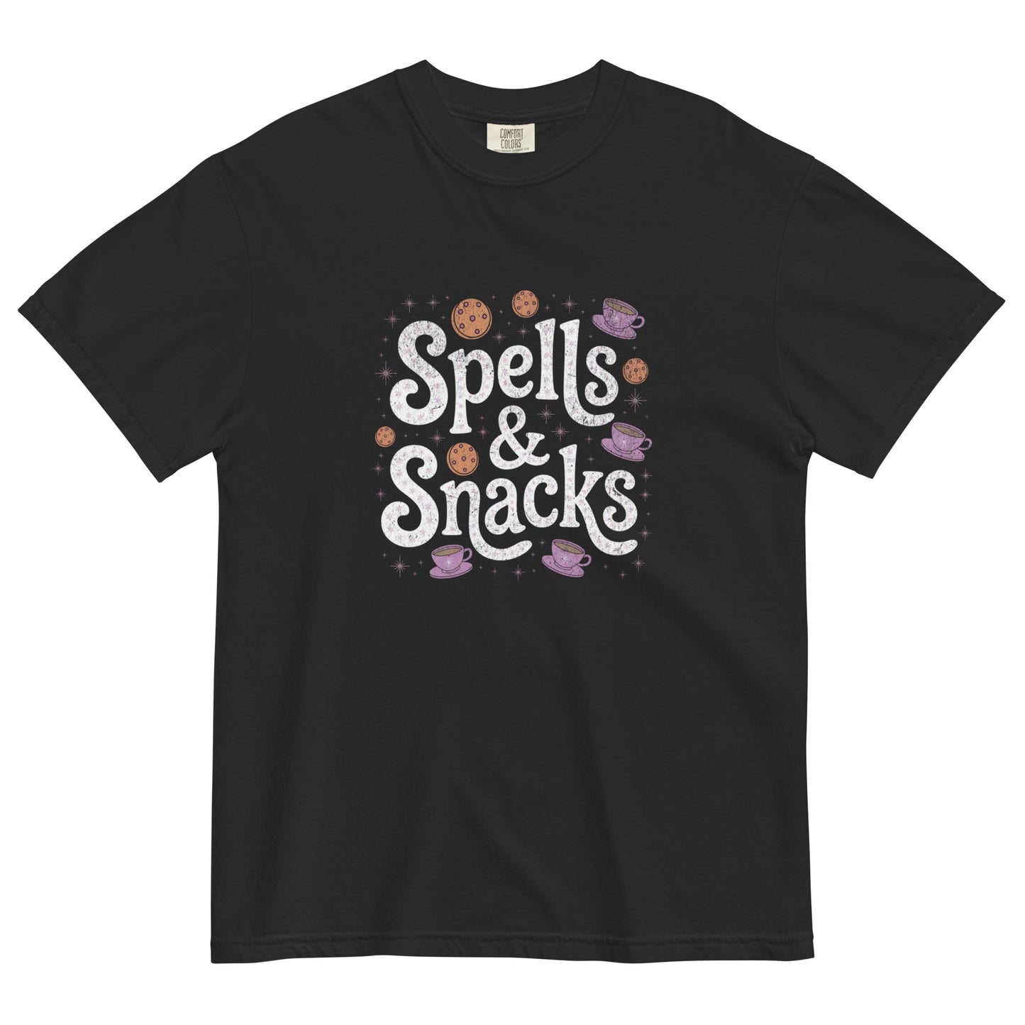 Black t-shirt lay flat featuring white “Spells & Snacks” text surrounded by pastel cookies, stars, and potion bottles — a cute witchy cottagecore graphic tee.