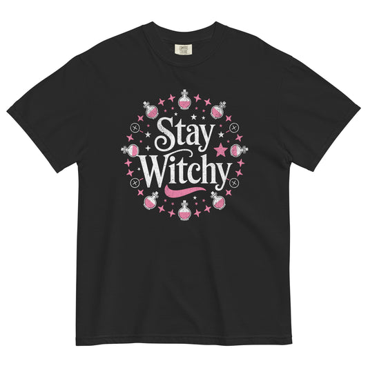 Black t-shirt lay flat featuring whimsical white “Stay Witchy” text surrounded by pink stars, potions, and moons — a playful magical graphic tee for modern witches.