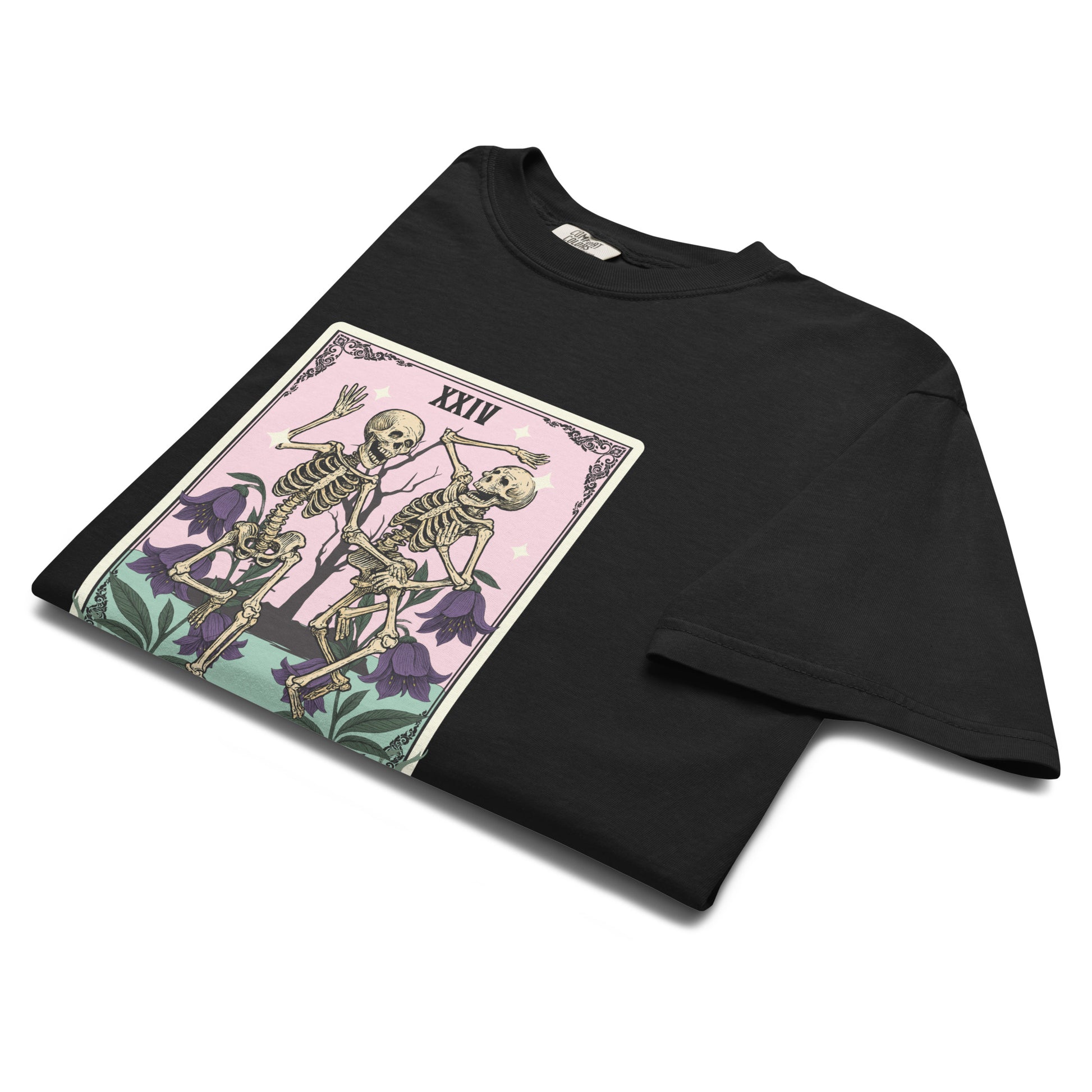 Folded black “The Humerus” t-shirt flat lay featuring pink and green tarot illustration with skeletons, perfect for gothic or witchy humor lovers.