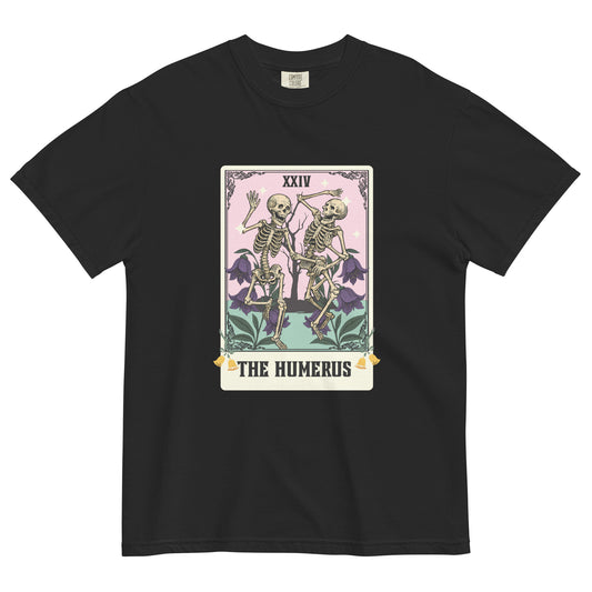 Black t-shirt lay flat featuring “The Humerus” tarot card-style design with two skeletons and floral details, a witty occult-inspired graphic tee with pastel tones.