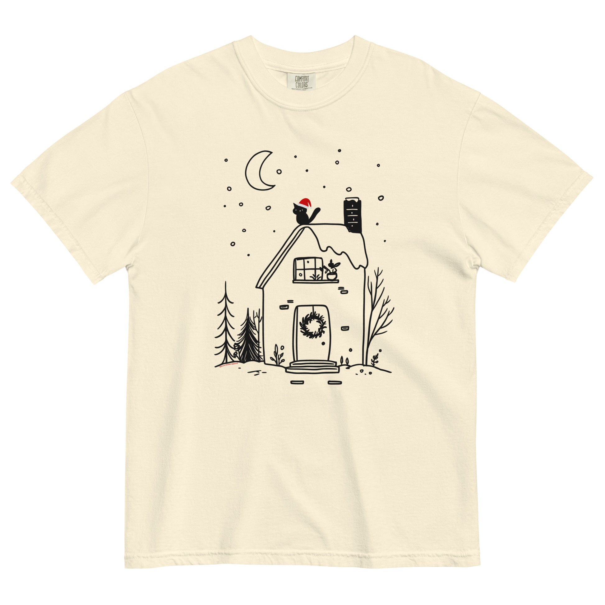 Ivory Comfort Colors T-shirt with cozy witchy cottage design featuring moon, wreath, and snow, shown lay flat on white background.